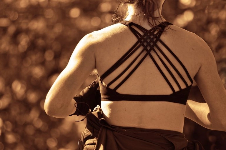 A sepia colored photography of the back of a woman in athletic apparel.