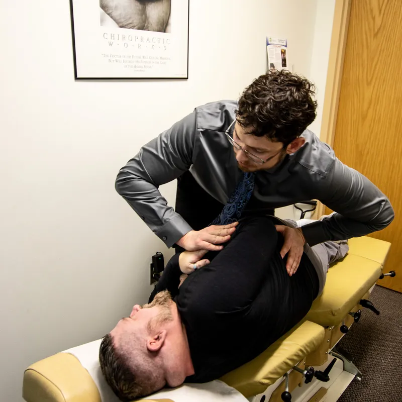 Evaluating a patient's lower back movement and performing a chiropractic adjustment.