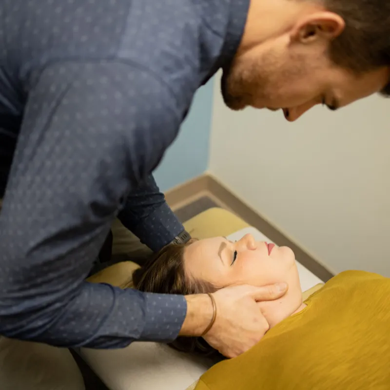 Doctor Boll evaluating a patient's cervical spine movement to help treat her neck pain and headaches.