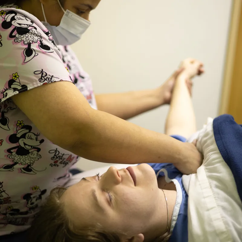 Performing massage therapy on a patient's shoulder.