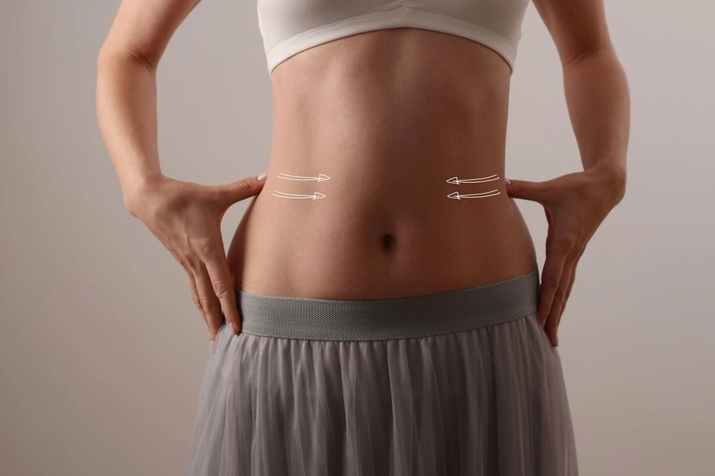 A woman's waist while she has her hands on the sides with arrows pointing from the edge of the waist to the center.
