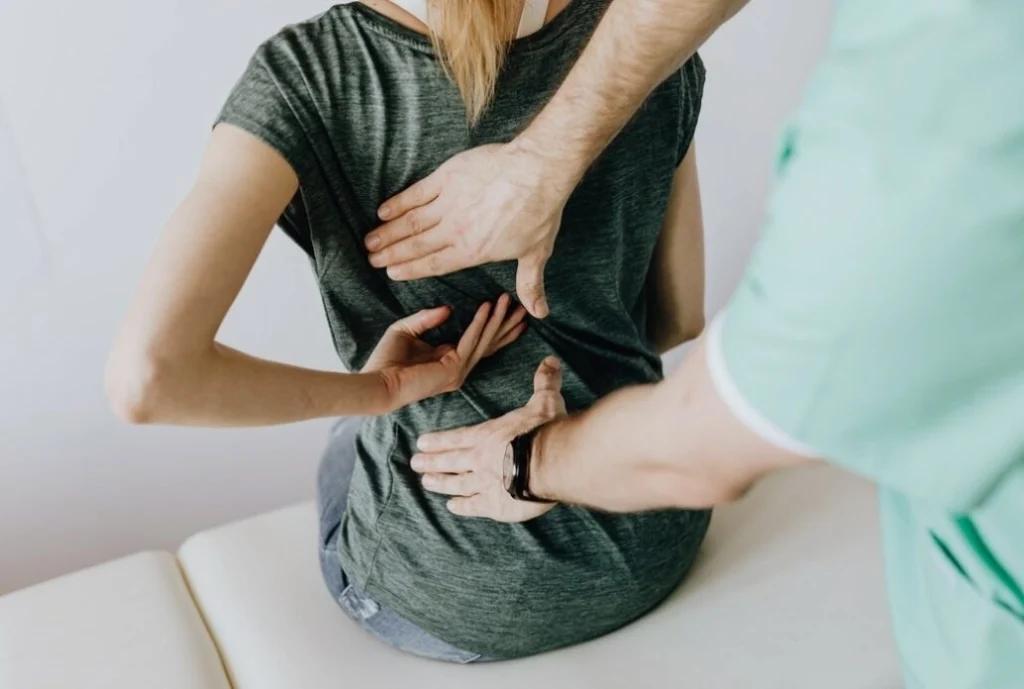 A woman's back getting checked by a chiropractor.