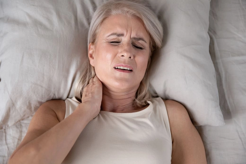woman on the bed with neck pain-min