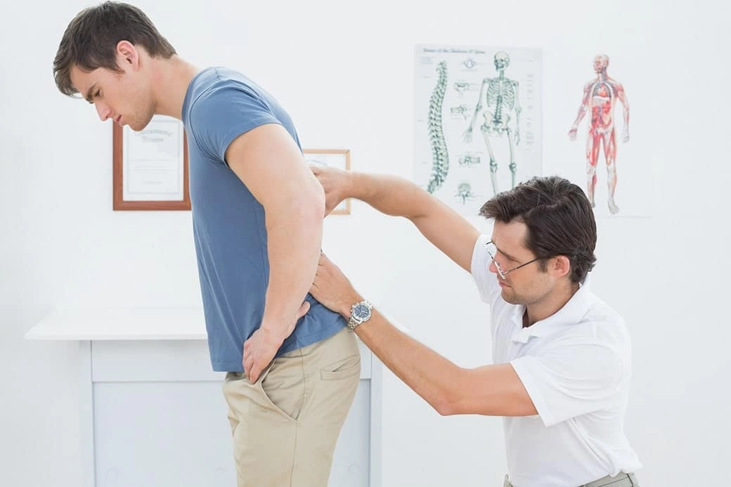 A young man getting checked on his lower back by a chiropractor.