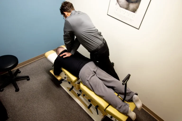 A chiropractor attending to a patient's upper back.