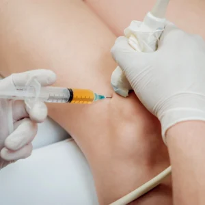 A knee getting injected with an orange substance.