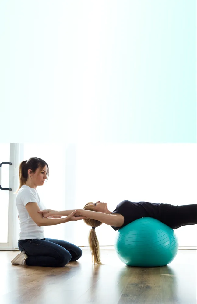A physical therapist facilitating back exercises for a patient.
