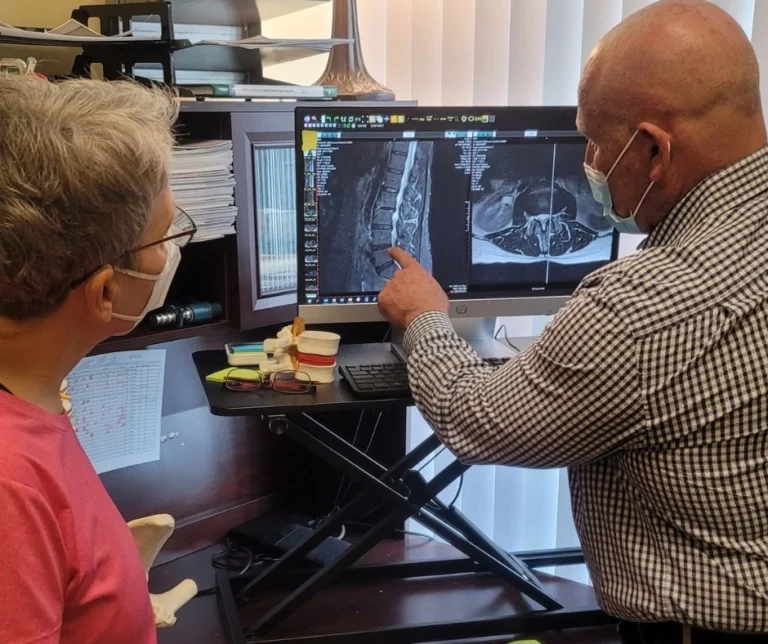 Dr. Brent Wells explaining an x-ray image of a back to a patient.