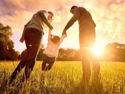 A family playing in the countryside in the sunset.