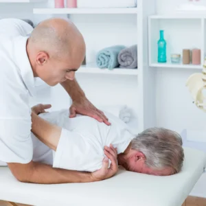 An elderly man having treatment by a chiropractor on their shoulder.