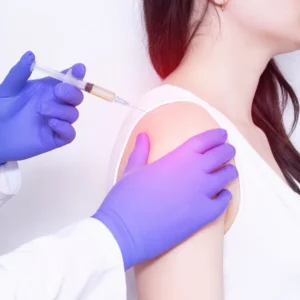 A woman getting an injection in the back of her shoulder.