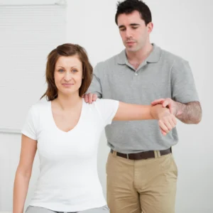 A chiropractor checking a woman's shoulder movement.