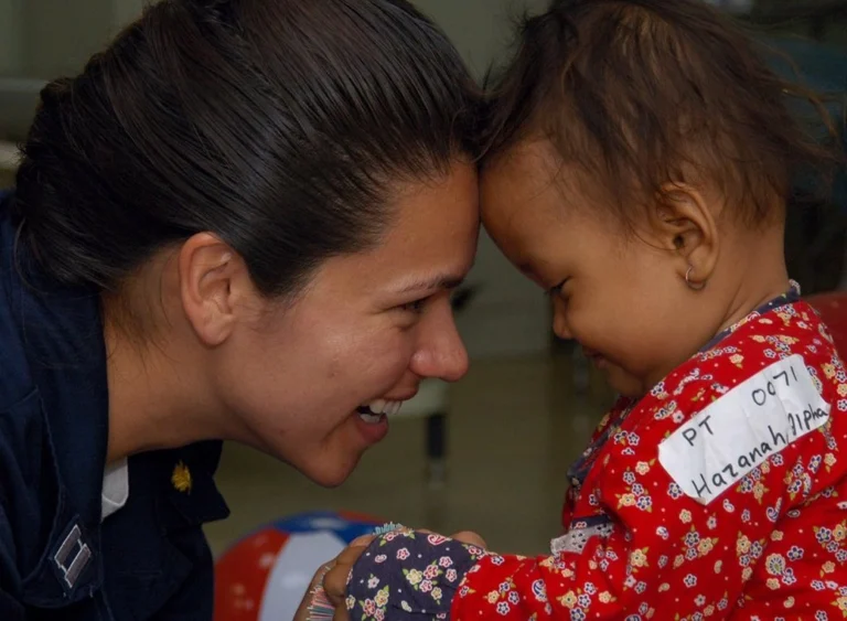 A lieutenant of police looking at a young baby and smiling.
