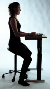 A woman sitting ergonomically in front of a keyboard.