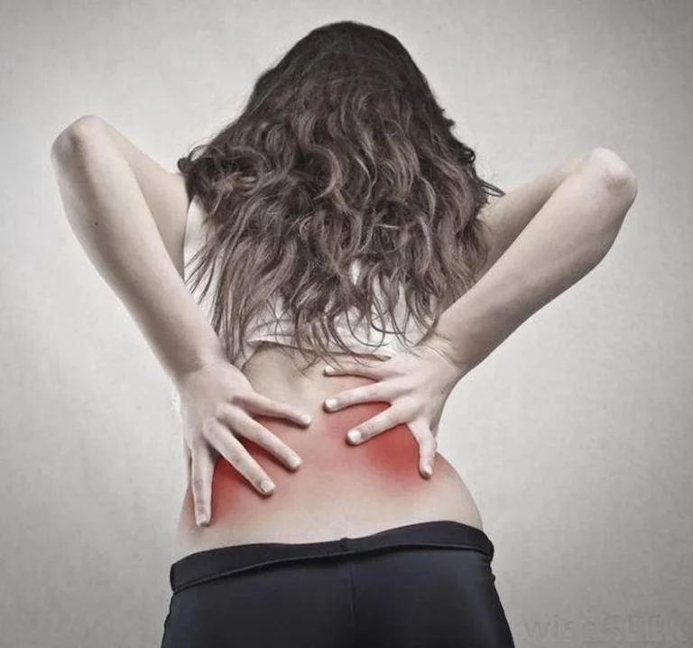 A woman touching her back in pain.
