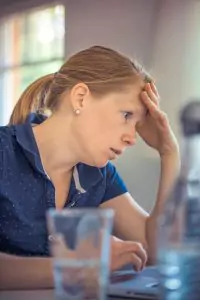 A woman looking stressed and holding her head.