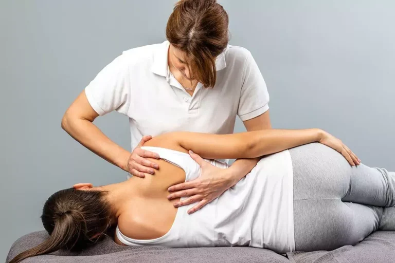 A woman getting chiropractic treatment while lying on her side.
