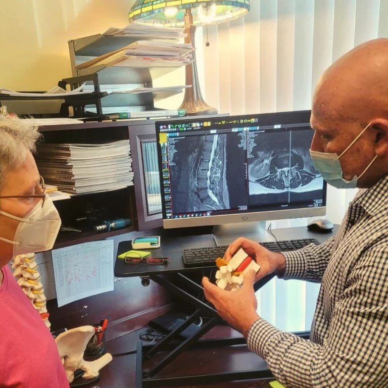 Dr. Brent Wells Explaining a condition to a patients, using x-ray images and medical anatomy dummies of spinal sections.