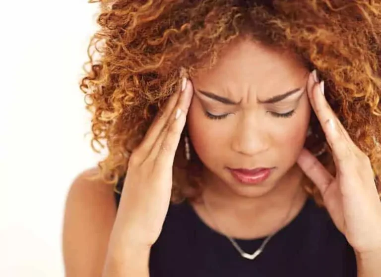 A woman touching the sides of her forehead in pain.