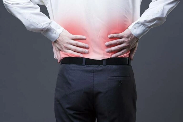 A man touching his lower back in pain.
