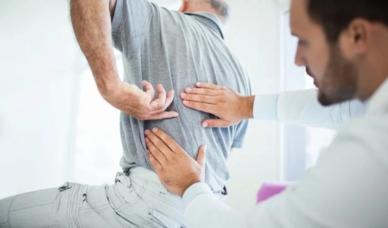 A man getting his lower back checked by a chiropractor.