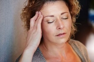 A woman touching her forehead to alleviate the pain.