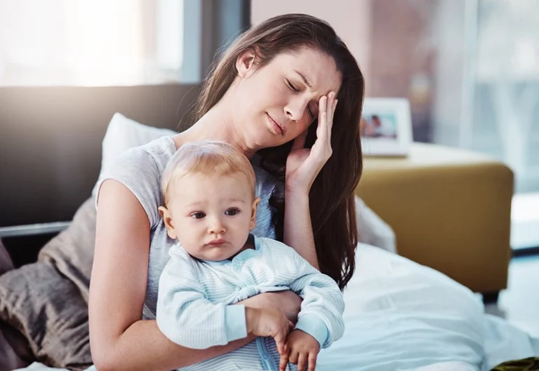 A woman with her baby having a headache.