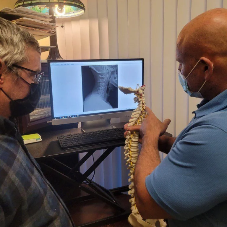 Dr. Brent Wells Explaining a condition to a patients, using x-ray images and medical anatomy dummies of spinal sections.