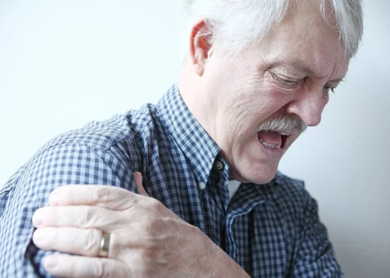 An old man feeling pain in his shoulder.