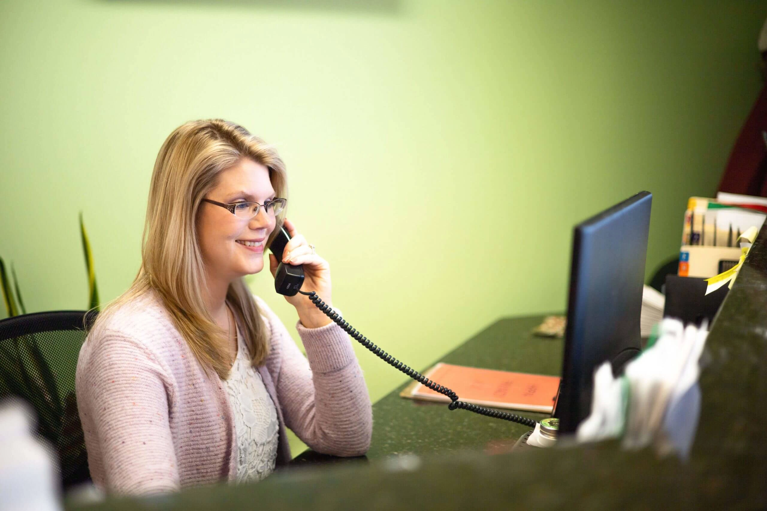 A woman answering phone calls in a reception desk.