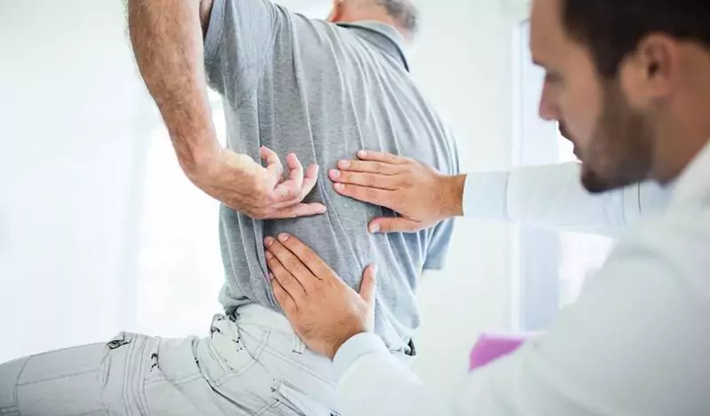 A man having his lower back checked by a chiropractor.