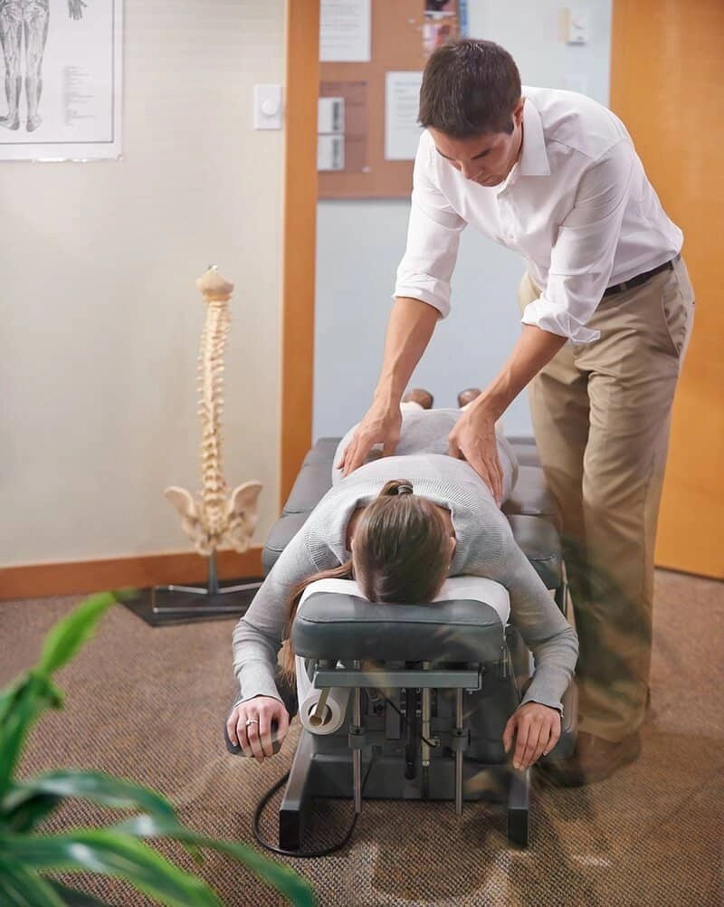 A woman being treated by a chiropractor on her back.