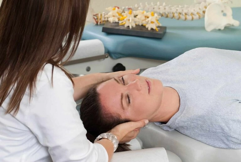 A woman having her neck treated by a chiropractor.