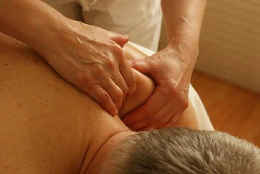 A man having his shoulder and neck treated with massage.
