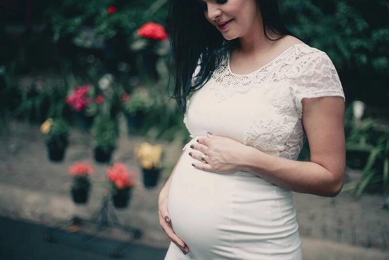 A pregnant woman touching her belly and smiling.