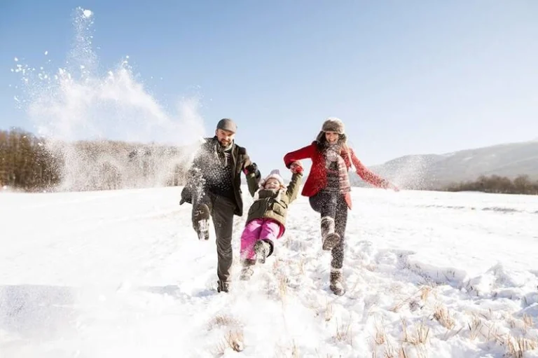 A family of three walking in a snowy area.