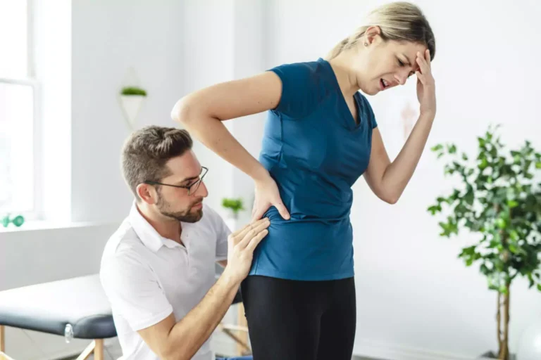 A chiropractor examining a woman with pain in her lower back.