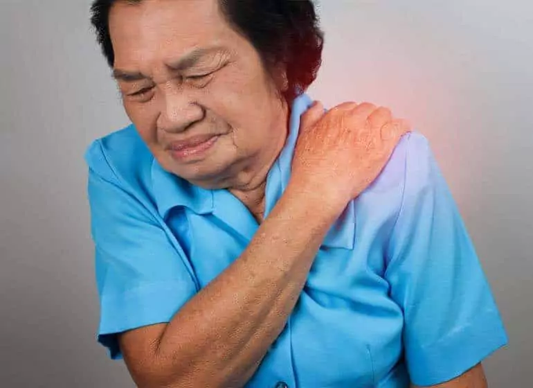 A person touching their shoulder in pain.