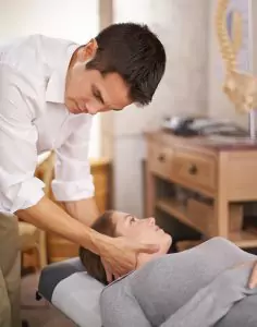 A woman having her neck treated by a chiropractor.