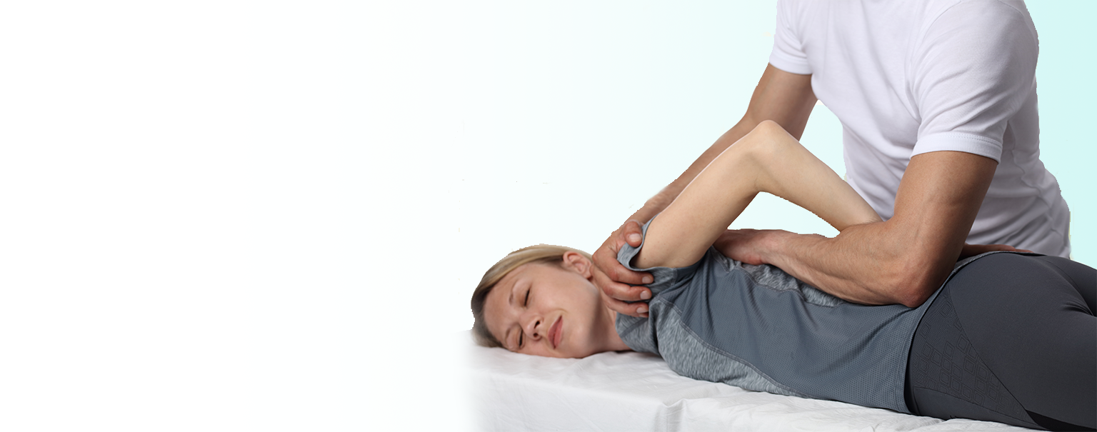 A female patient receiving chiropractic treatment in her left shoulder while lying face down.