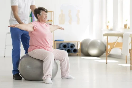 An elderly woman having help with some exercises.